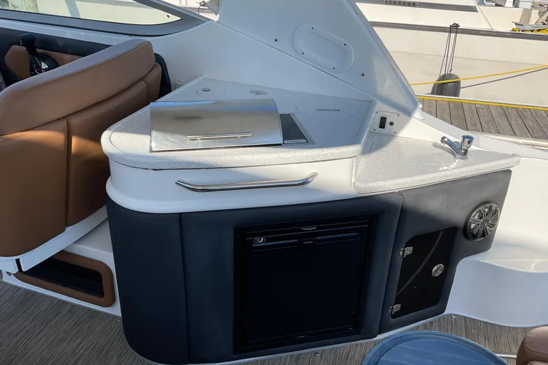 Slide: The Image of 2019 Rinker 290 Express Cruiser interior with kitchenette and seating area. - 6