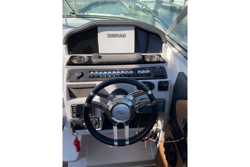 Slide: The Image of 2019 Rinker 290 Express Cruiser helm with Simrad display and modern controls. - 9