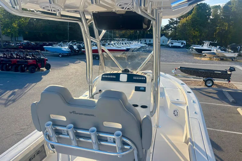 Slide: The Image of 2026 Avenger AV26 boat interior with helm, rod holders, and parked vehicles in background. - 22