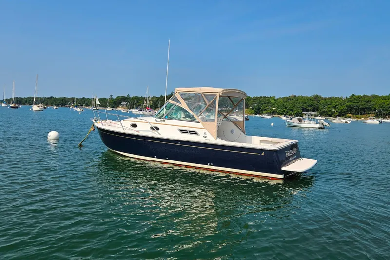 The Image of 2006 Back Cove 26 boat on calm water, surrounded by other boats and lush greenery. - 0