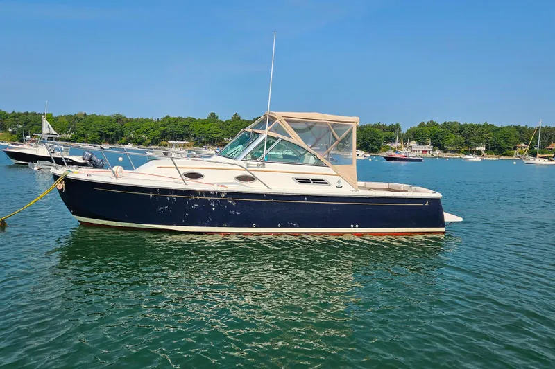Slide: The Image of 2006 Back Cove 26 boat on calm water, surrounded by lush greenery and other boats. - 1