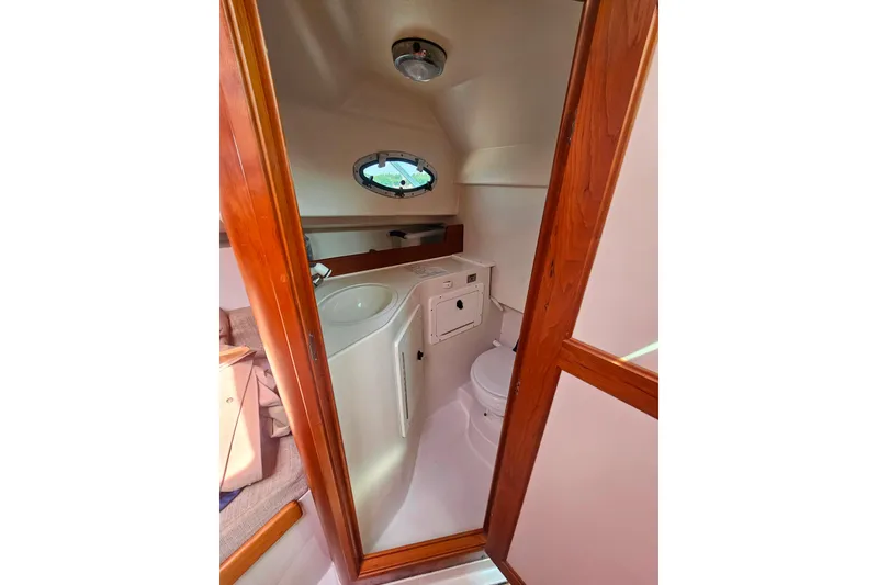 Slide: The Image of 2006 Back Cove 26 boat interior with compact bathroom and wooden door. - 21