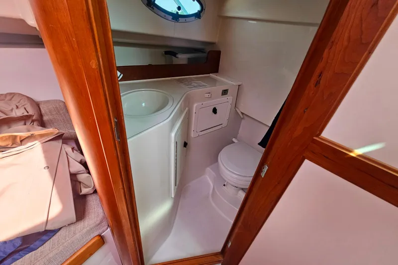 Slide: The Image of 2006 Back Cove 26 boat interior with compact bathroom and wooden accents. - 22