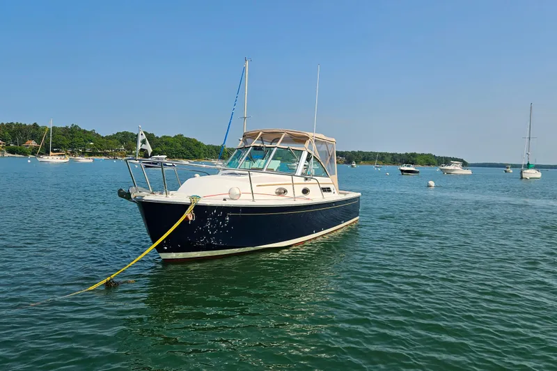 Slide: The Image of 2006 Back Cove 26 boat anchored in a scenic bay with other vessels. - 3
