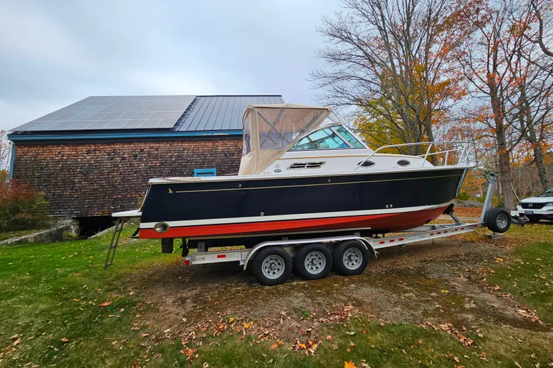 Slide: The Image of 2006 Back Cove 26 boat on trailer, parked near a building with solar panels. - 31