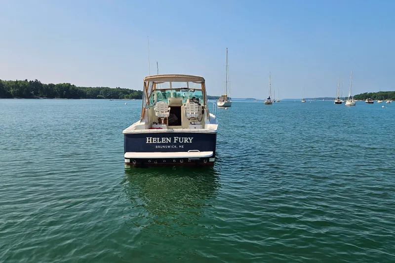 Slide: The Image of 2006 Back Cove 26 boat named "Helen Fury" on calm water, surrounded by sailboats. - 9
