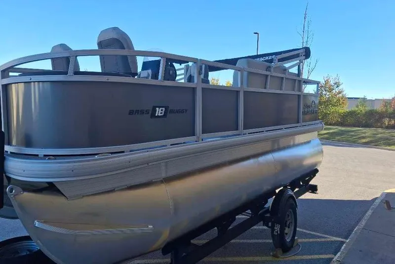 Slide: The Image of 2026 Sun Tracker Bass Buggy 18 DLX pontoon boat on trailer, parked outdoors. - 34