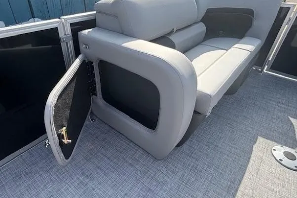 Slide: The Image of 2026 Sun Tracker Party Barge 22 RF DLX with open storage compartment and gray seating. - 13