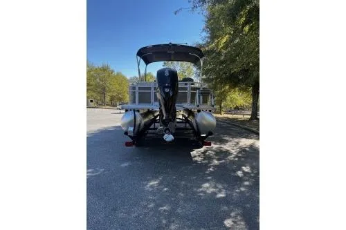 Slide: The Image of 2026 Sun Tracker Fishin' Barge 22 DLX pontoon boat parked under trees. - 3
