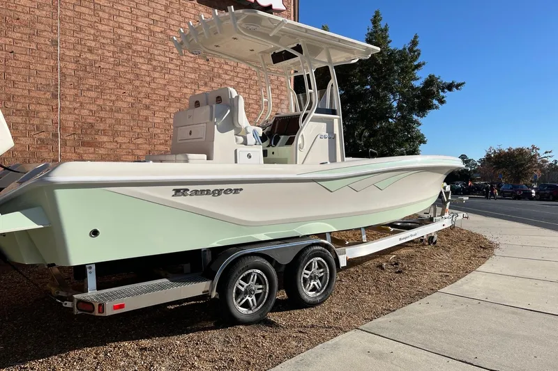 Slide: The Image of 2024 Ranger 2600 Bay boat on trailer, parked outdoors near brick wall. - 6