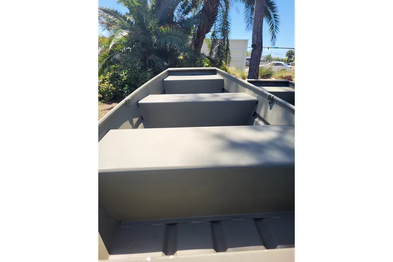 The Image of 2026 Tracker Grizzly 12 Jon boat interior with bench seats, surrounded by palm trees. - 0