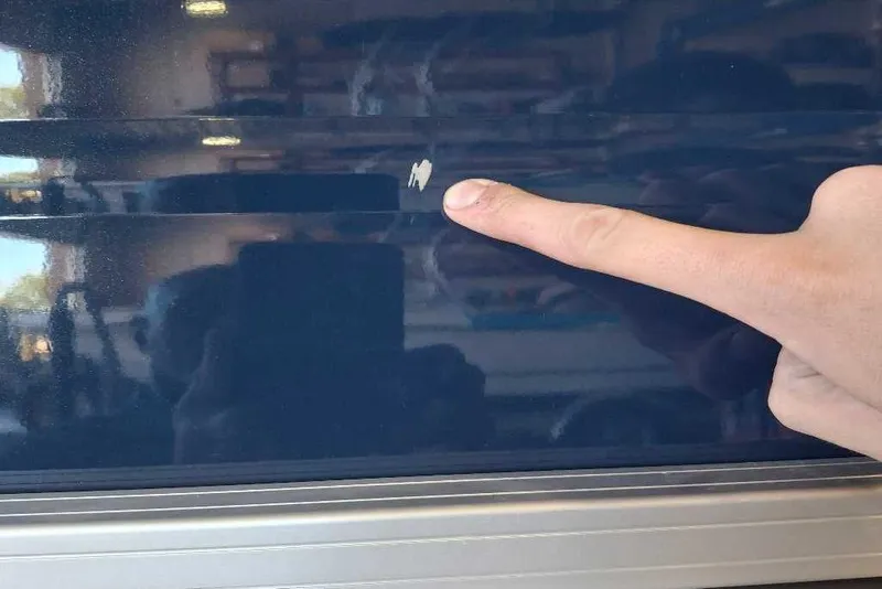 Slide: The Image of Finger pointing at scratch on 2026 Sun Tracker SportFish 20 DLX boat surface. - 82