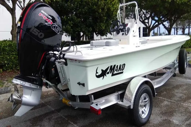 Slide: The Image of 2026 Mako 18 Pro Skiff boat on trailer with outboard motor, parked outdoors. - 5