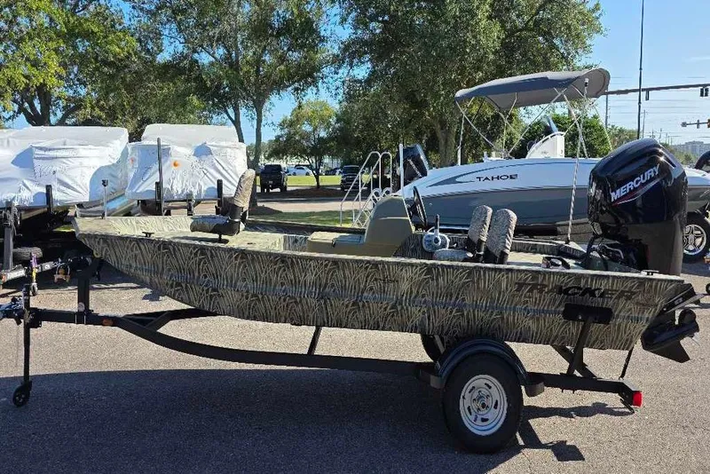 The Image of 2026 Tracker Grizzly 1754 SC boat with camouflage design on a trailer, parked outdoors. - 0
