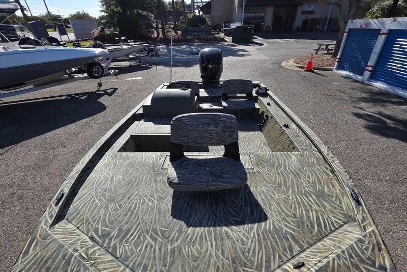 Slide: The Image of 2026 Tracker Grizzly 1754 SC boat with camouflage design in a parking area. - 2