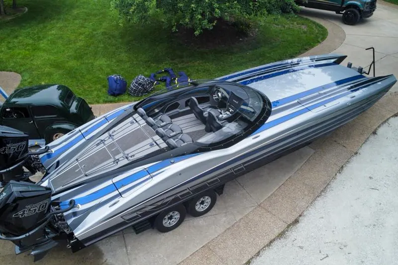 Slide: The Image of 2019 MTI 340X powerboat with dual Mercury 450 engines, parked on a driveway. - 2