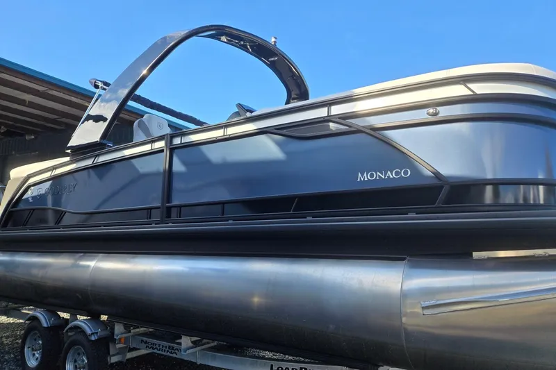Slide: The Image of 2026 Godfrey Monaco 235 ULC pontoon boat on trailer, sleek design under clear blue sky. - 7