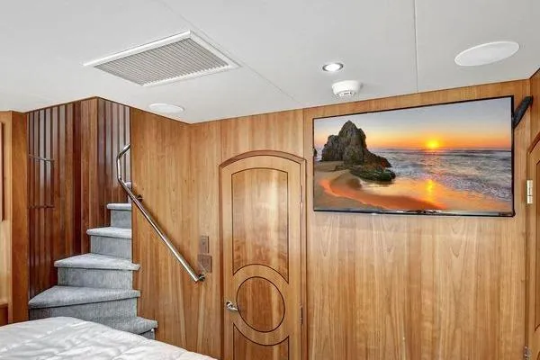 Slide: The Image of Luxurious 2005 Hatteras 100 Motor Yacht interior with wood paneling and mounted TV. - 32