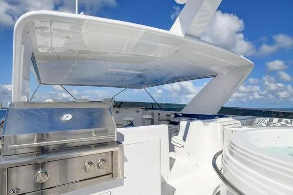 Slide: The Image of Luxury 2005 Hatteras 100 Motor Yacht deck with grill and jacuzzi under blue sky. - 50