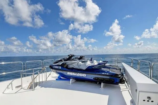 Slide: The Image of 2005 Hatteras 100 Motor Yacht deck with Sea-Doo jet skis under a clear blue sky. - 53