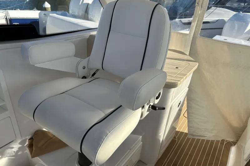 Slide: The Image of Captain's chair on 2020 Southport 33DC boat, featuring white upholstery and armrests. - 19