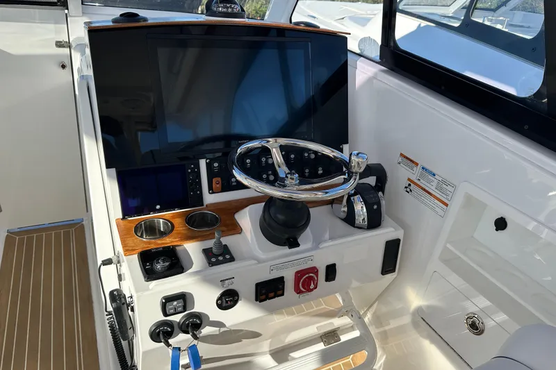Slide: The Image of 2020 Southport 33DC boat helm with steering wheel, controls, and navigation display. - 23