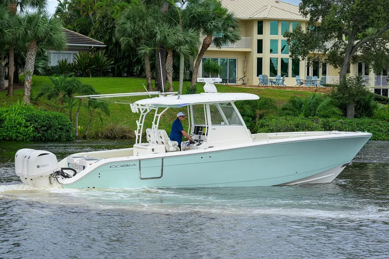 Slide: The Image of 2020 Cobia 350 CC boat cruising on a scenic waterway near a luxurious house. - 11