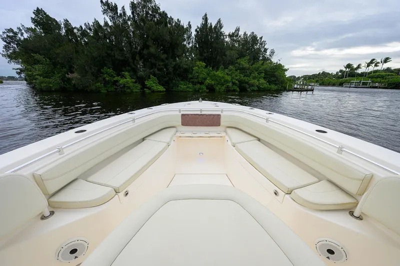 Slide: The Image of 2020 Cobia 350 CC boat interior with spacious seating, near lush greenery and calm waters. - 14
