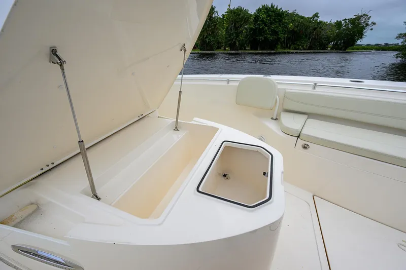 Slide: The Image of 2020 Cobia 350 CC boat with open storage compartments, docked by a scenic river. - 22