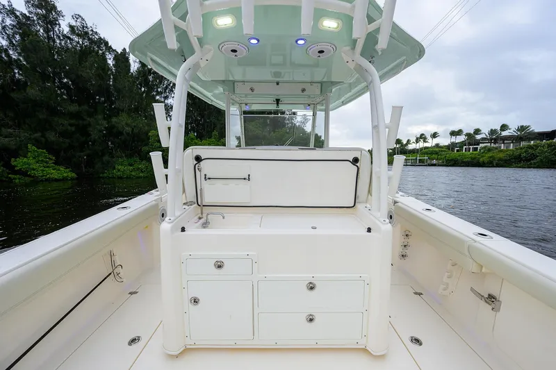 Slide: The Image of 2020 Cobia 350 CC boat interior with storage compartments and canopy on a calm waterway. - 35