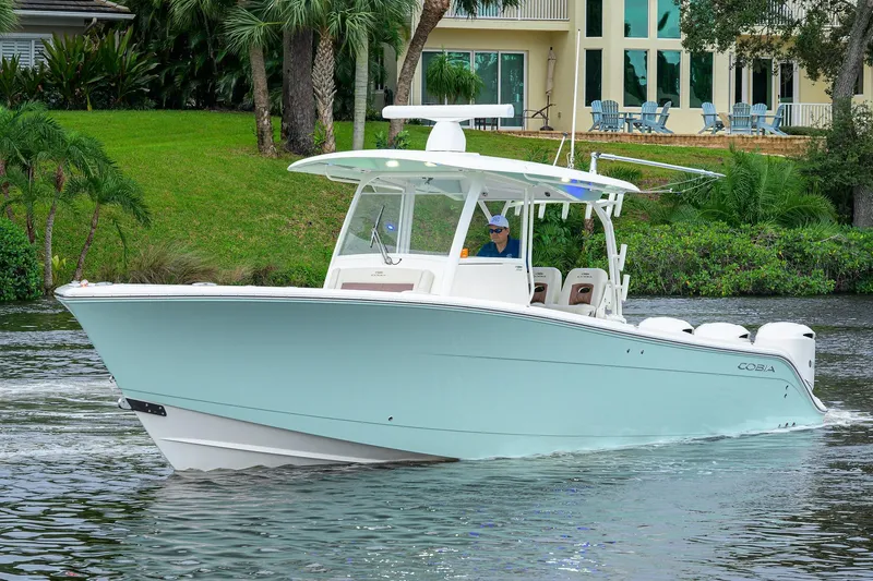 Slide: The Image of 2020 Cobia 350 CC boat cruising on a scenic waterway near a lush, green shoreline. - 4