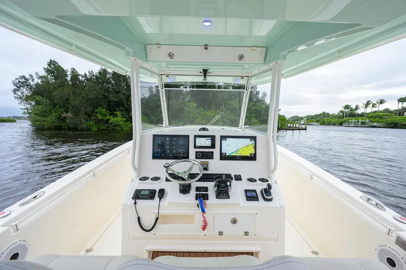 Slide: The Image of 2020 Cobia 350 CC boat cockpit with advanced navigation systems on a scenic waterway. - 43