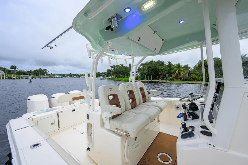 Slide: The Image of 2020 Cobia 350 CC boat interior with seating and controls, docked on a scenic waterway. - 46