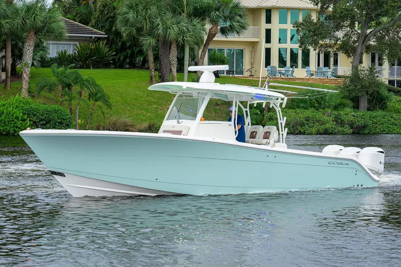 Slide: The Image of 2020 Cobia 350 CC boat cruising on a scenic waterway near a luxurious waterfront home. - 5