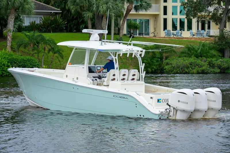 Slide: The Image of 2020 Cobia 350 CC boat cruising on a river with triple Yamaha engines. - 8