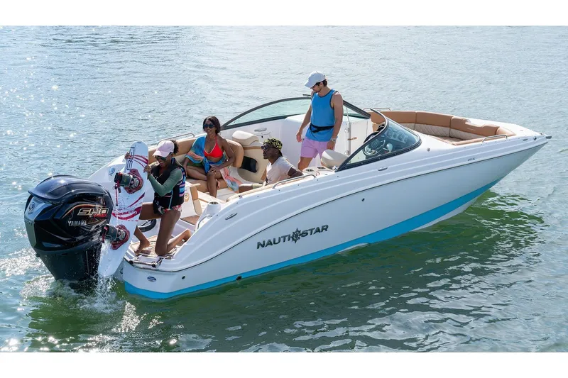 The Image of 2026 NauticStar 243 DC Deck boat displayed in showroom with blue and white exterior. - 0