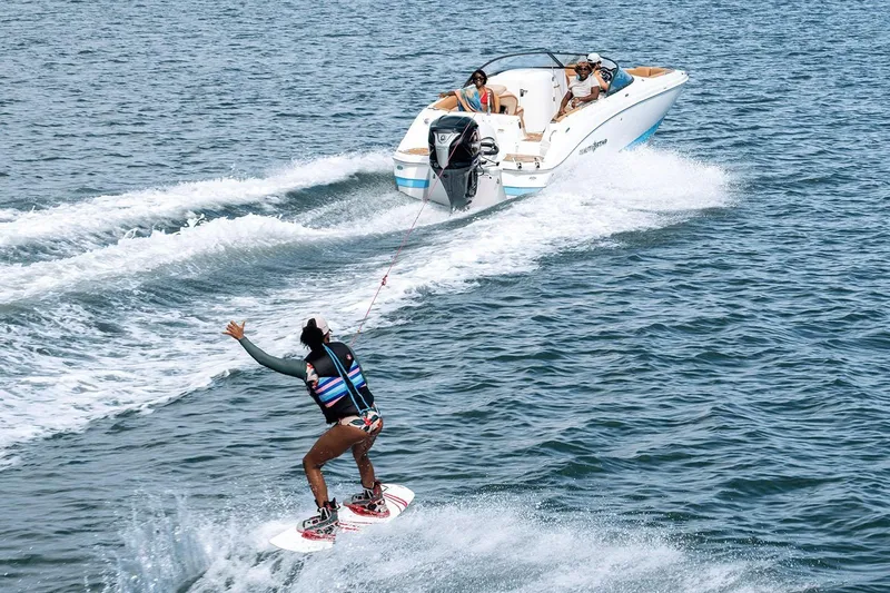 Slide: The Image of 2026 NauticStar 243 DC Deck boat displayed indoors, featuring blue and white design. - 2