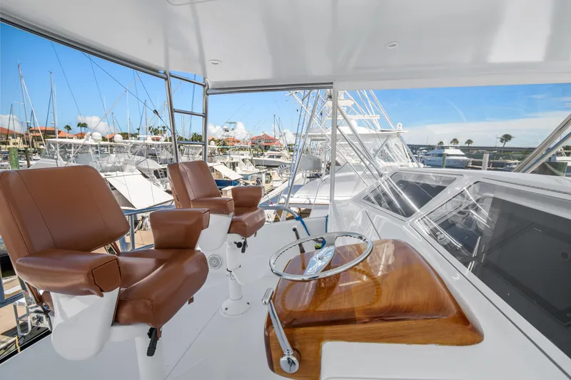 Slide: The Image of 2005 Viking 61 Convertible yacht helm with leather seats and marina view. - 12