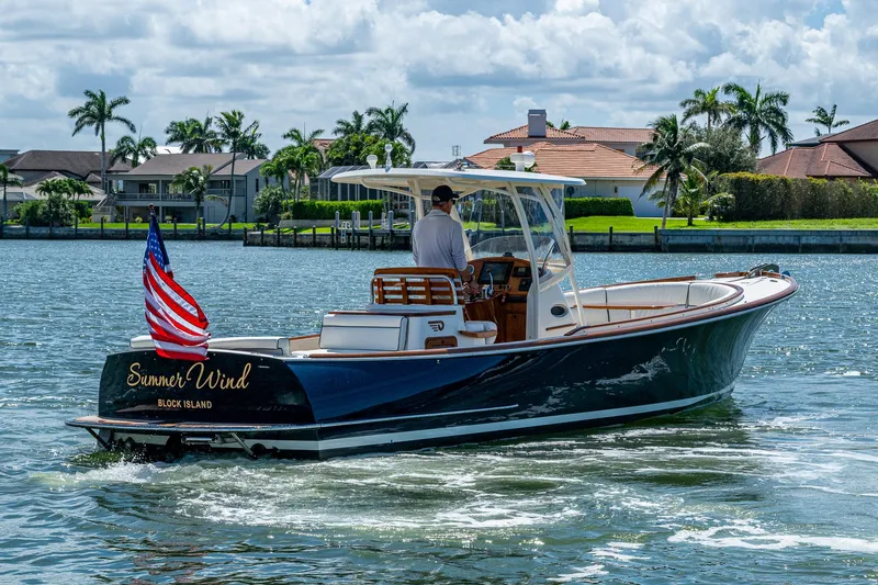 The Image of 2003 Hinckley Talaria 29 Center Console boat cruising near waterfront homes. - 0