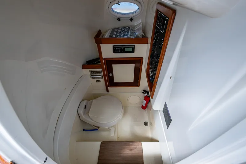 Slide: The Image of 2003 Hinckley Talaria 29 Center Console interior with toilet, control panel, and porthole. - 14