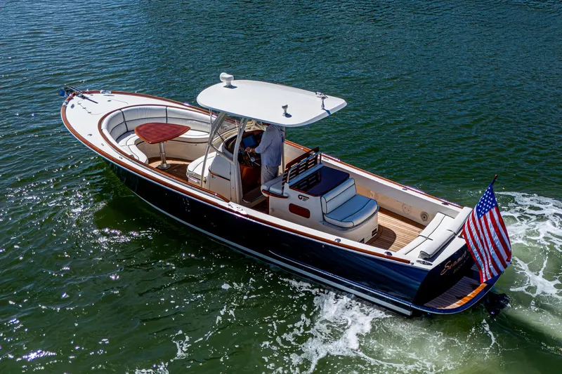 Slide: The Image of 2003 Hinckley Talaria 29 Center Console boat cruising on water with American flag. - 3