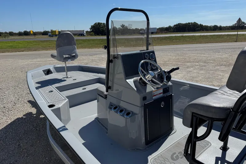 Slide: The Image of 2026 G3 21GX boat with steering console and seating, parked on gravel near highway. - 4