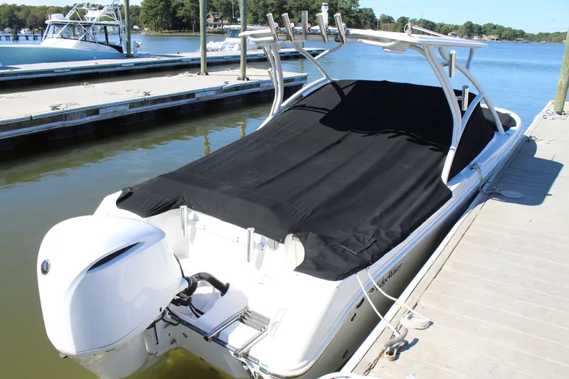 Slide: The Image of 2020 Edgewater 248CX Crossover boat docked with black cover, outboard motor visible. - 12