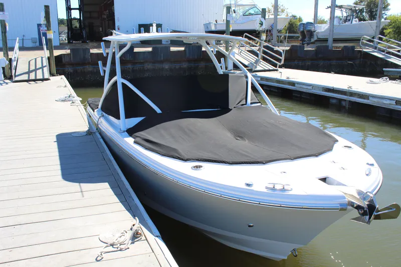 Slide: The Image of 2020 Edgewater 248CX Crossover boat docked with black cover, sunny day. - 14