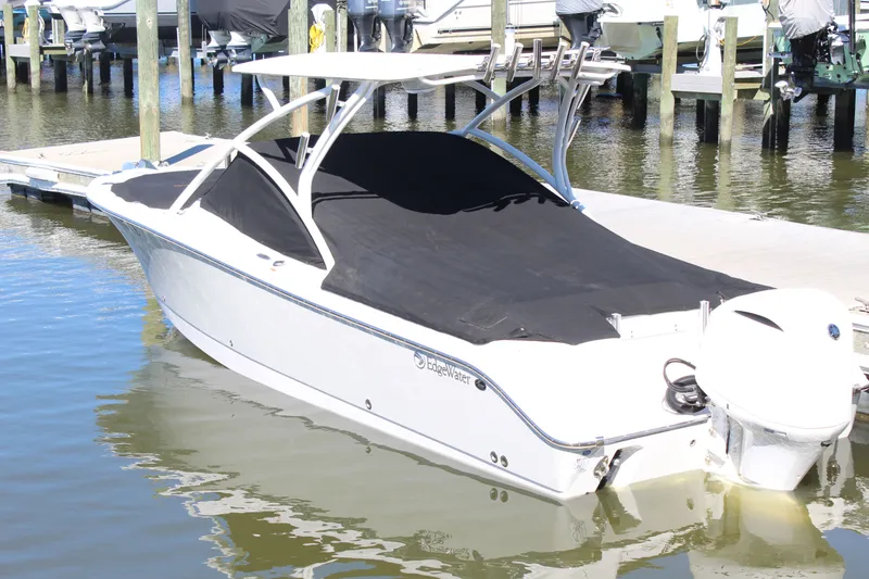 Slide: The Image of 2020 Edgewater 248CX Crossover boat docked with cover on, in a marina setting. - 15