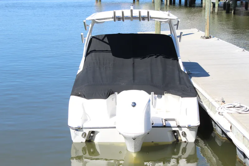 Slide: The Image of 2020 Edgewater 248CX Crossover boat docked with black cover, rear view. - 16