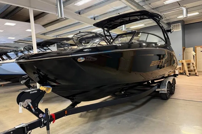 The Image of 2026 Yamaha Boats 255XD in showroom, sleek black design on trailer. - 0