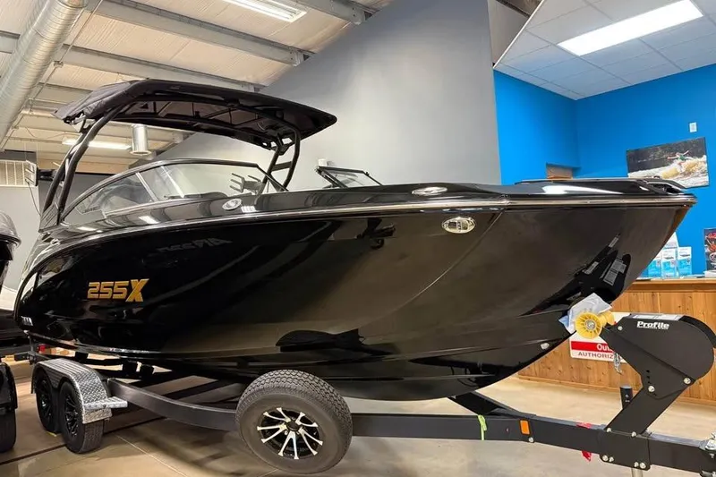Slide: The Image of 2026 Yamaha Boats 255XD in showroom, sleek black design on trailer. - 2