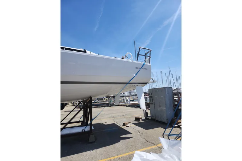 Slide: The Image of 2026 Jeanneau Sun Odyssey 350 sailboat on dry dock under clear blue sky. - 23