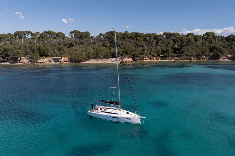 Slide: The Image of 2026 Jeanneau Sun Odyssey 350 sailing in clear turquoise waters near a forested coastline. - 5